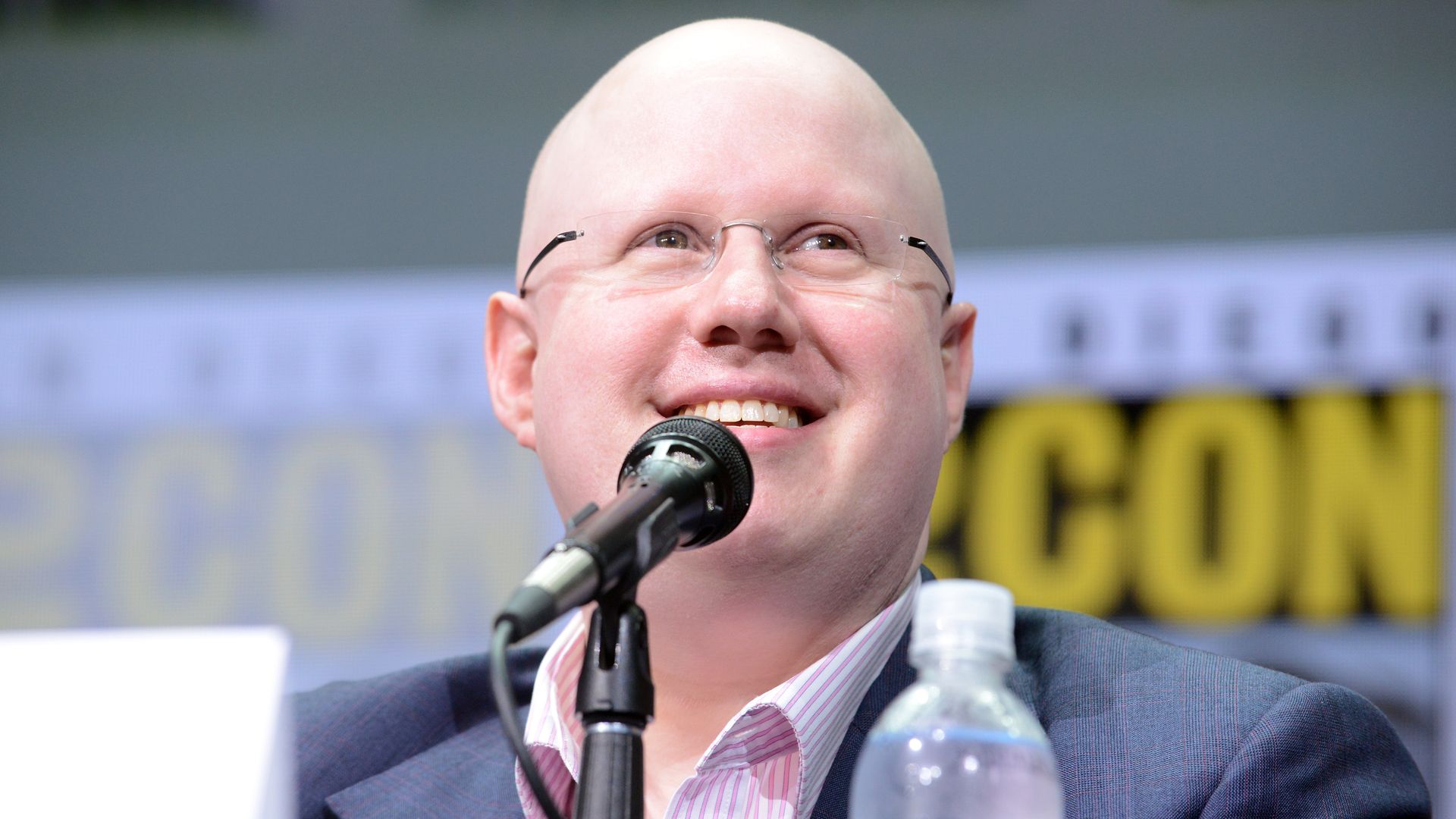 Matt Lucas smiling while sat on stage at comic con a mic is in front of him