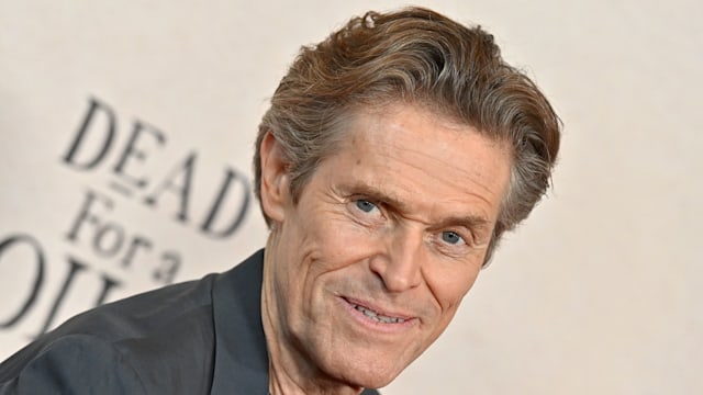 Willem Dafoe in grey suit jacket