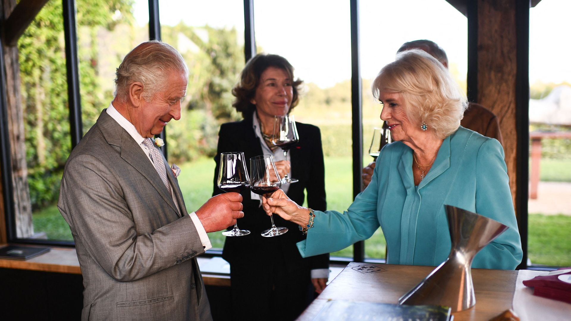 King Charles and Queen Camilla toasting glasses during visit to a vineyard in France