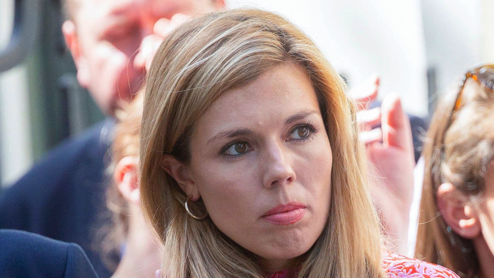 Carrie Johnson adjusting her hair in a pink dress