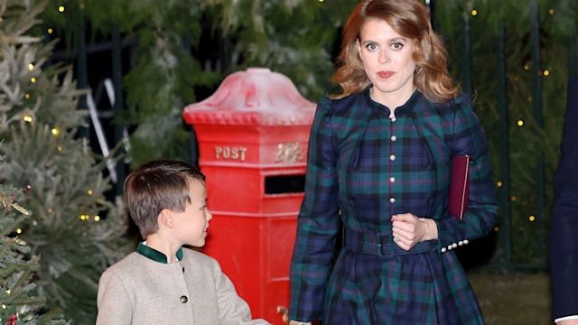 Princess Beatrice in a blue and green jacket holding hands with stepson Wolfie in front of Christmas trees