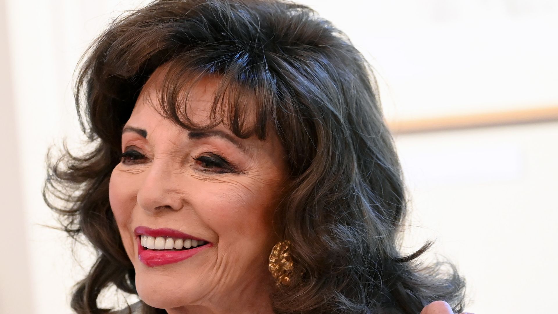 Joan Collins smiles at event