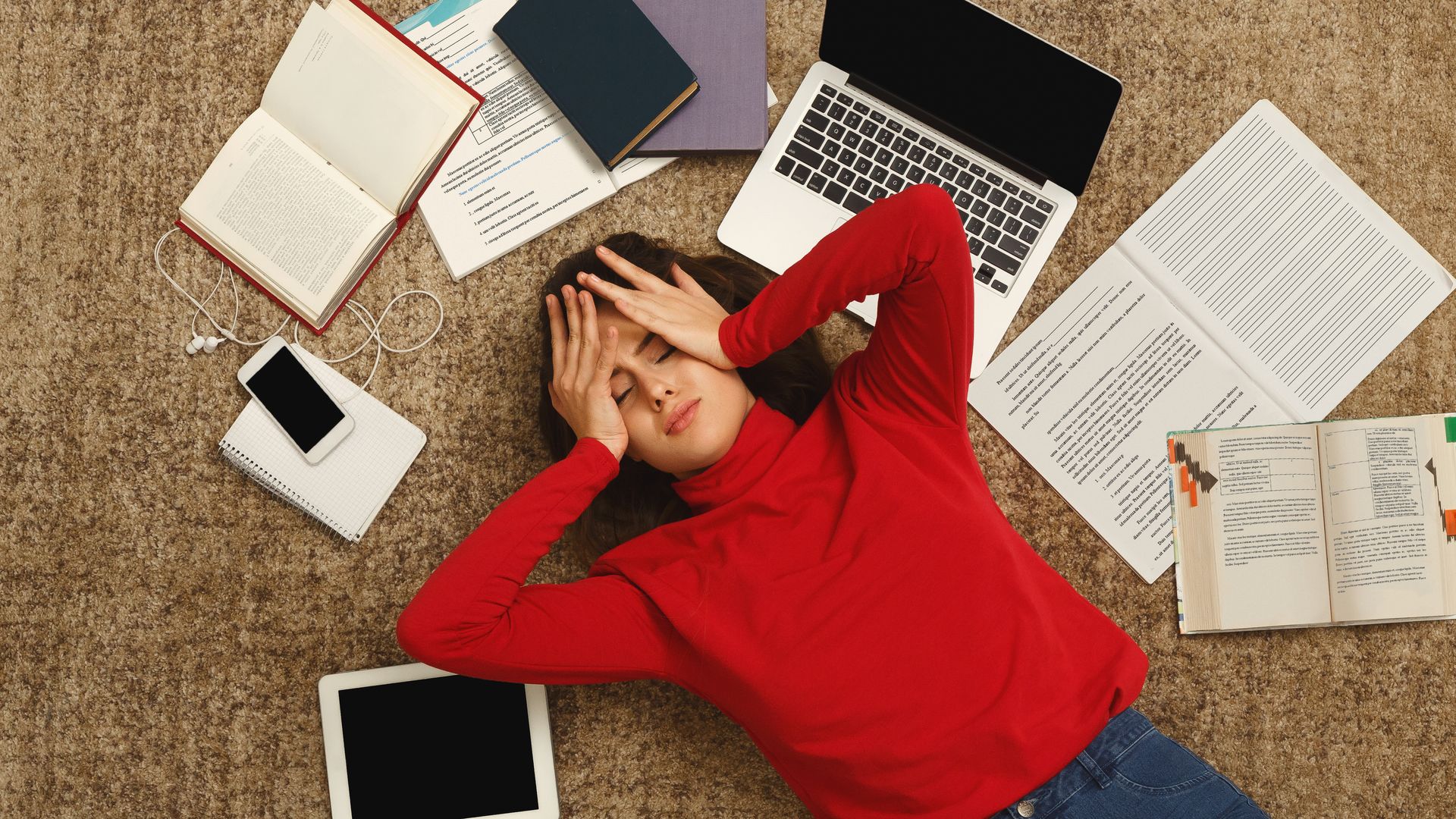 Exhausted student lying on the floor among textbooks and tests