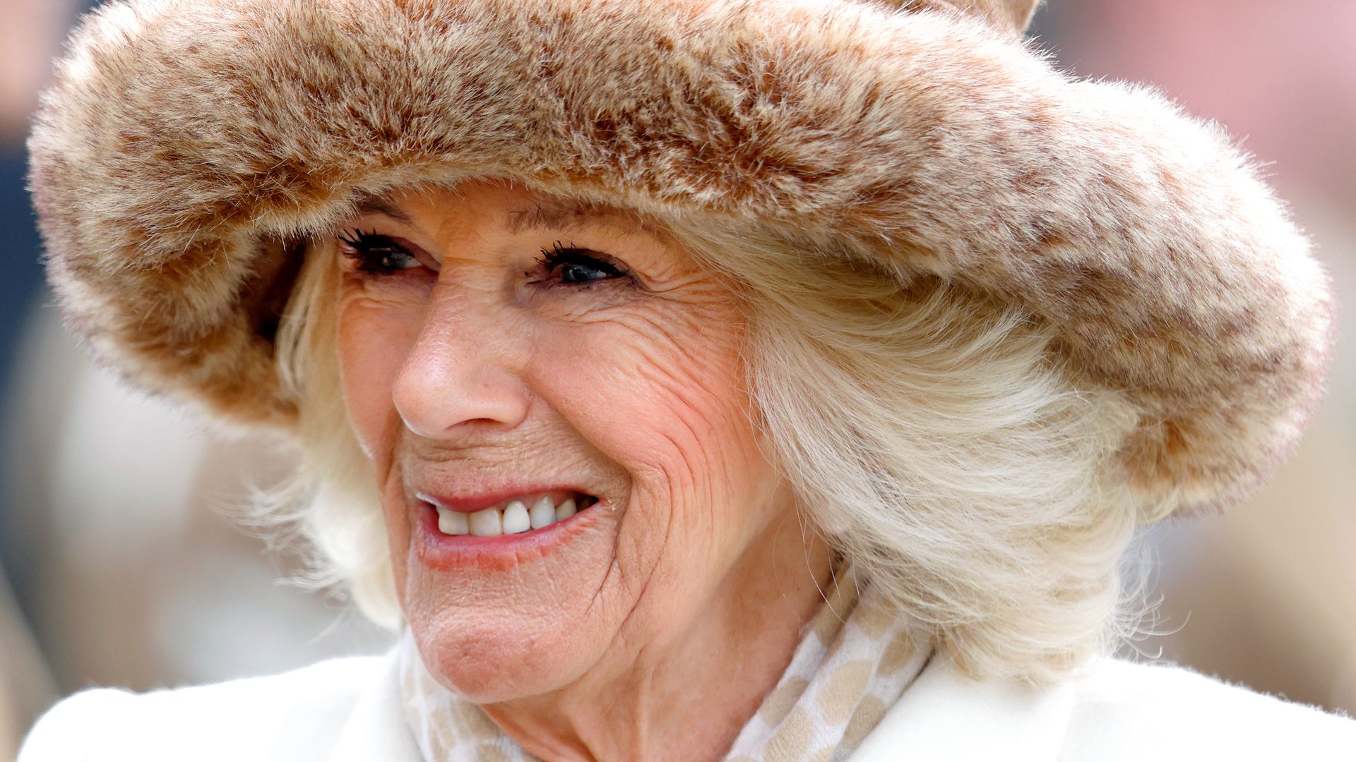 Queen Camilla smiling in beige fur hat