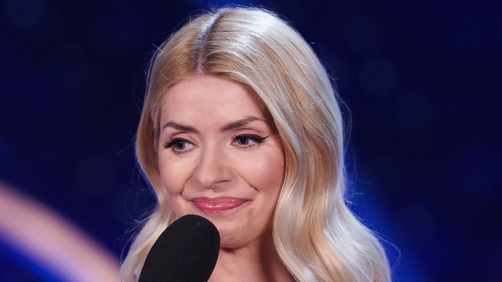 Holly Willoughby in sparkly dress holding mic to mouth