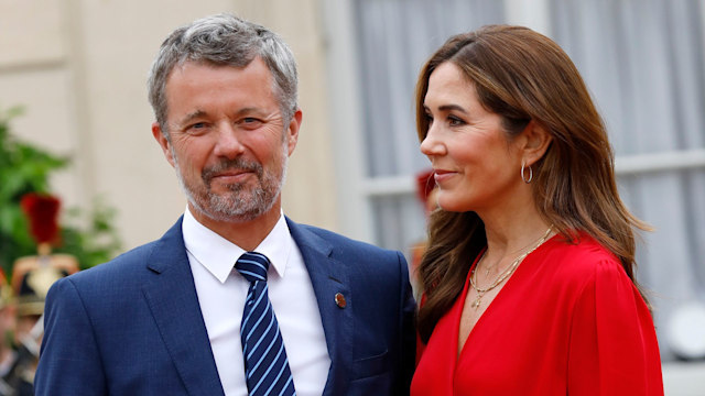 Queen Mary wearing red blouse looking at King Frederik