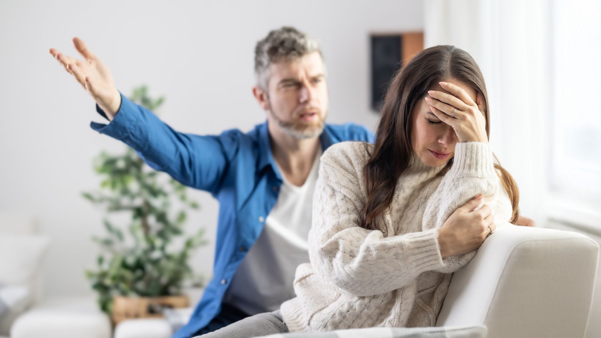 The husband shouts at the partner, who ignores him and holds her head in frustration