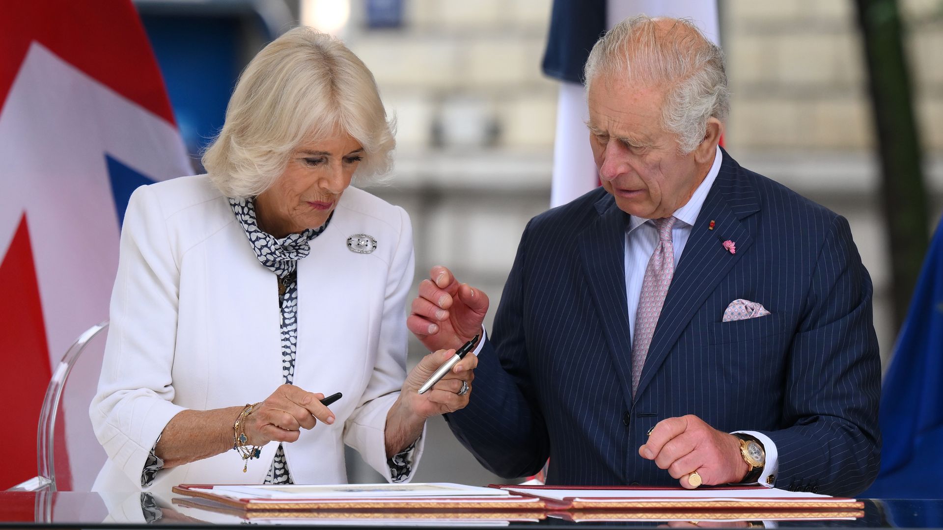 Queen Camilla and King Charles signing a book