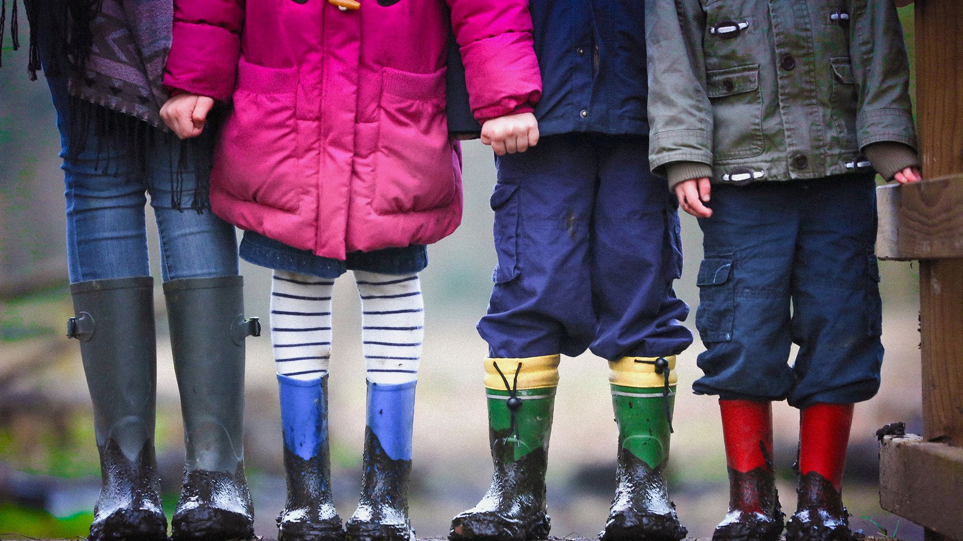 four children outdoors in wet weather clothing