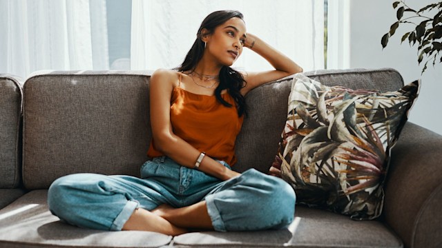 Shot of a young woman looking thoughtful while relaxing on the sofa at home