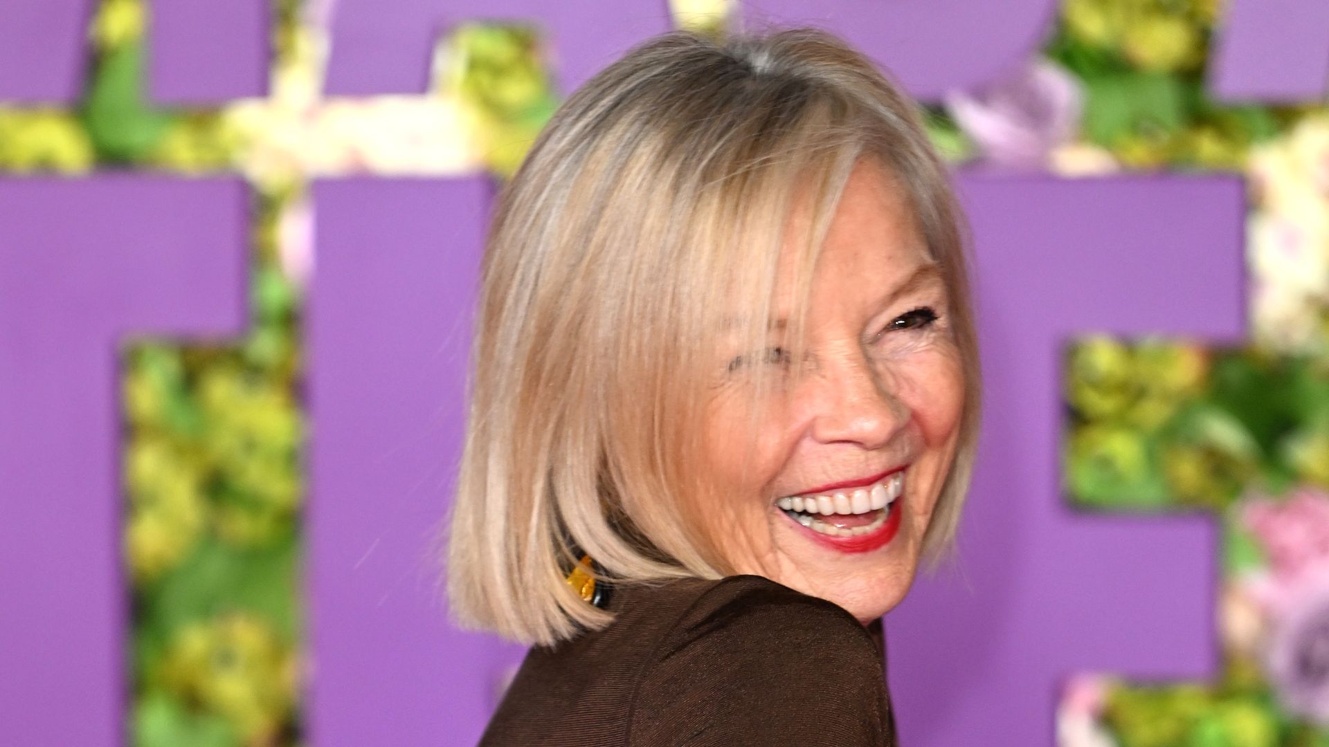 jo good in dark brown smiling over her shoulder wearing red lipstick