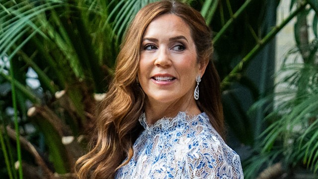 Queen Mary in blue lace dress surrounded by plants