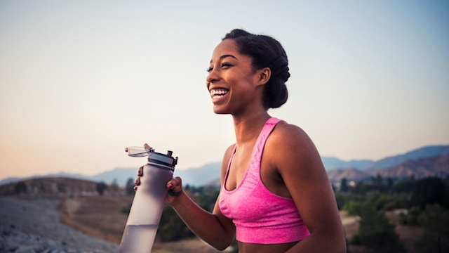 Happy female runner holding water bottle