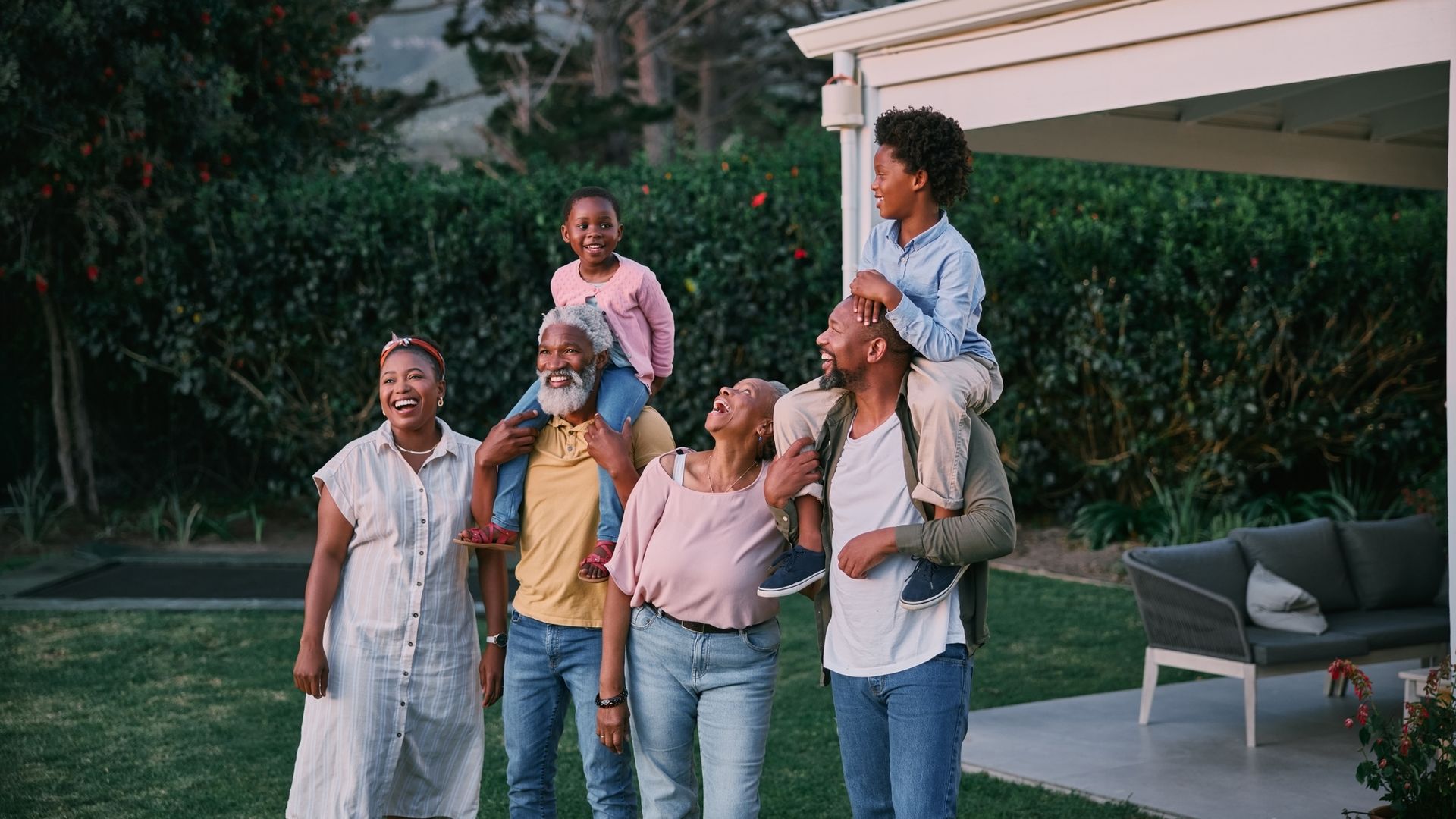 Kids, parents and grandparents together at a holiday home while outside in the garden at sunset