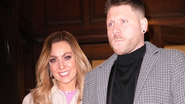 Amy Dowden in a pink dress and white coat arm in arm with her husband