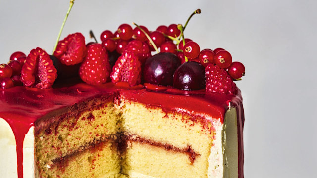 A drip cake with madeina cake and vanilla buttercream topped with cherries and strawberries