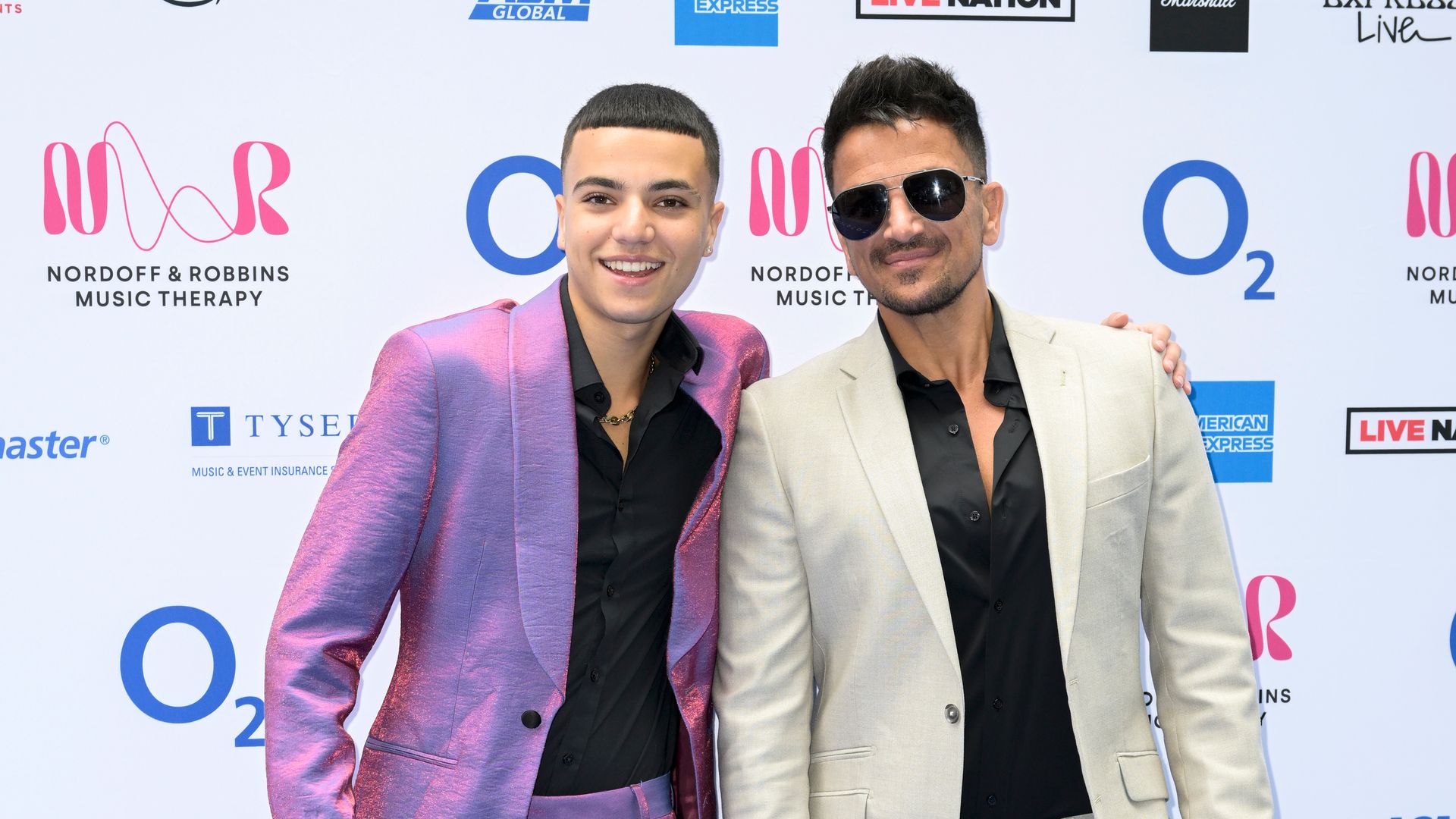 Junior Andre in purple suit stood with Peter Andre in white suit
