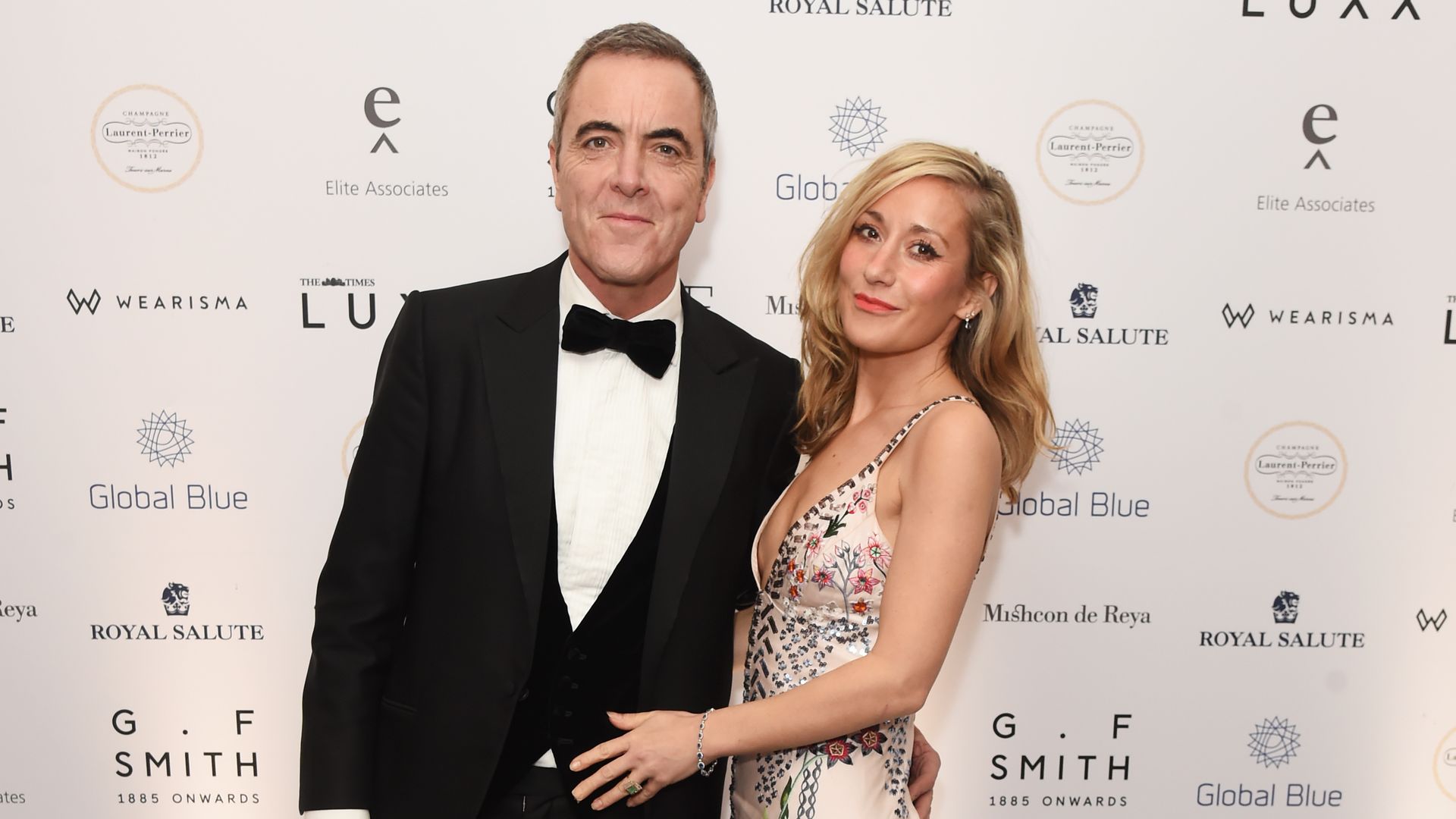 James Nesbitt in a tuxedo standing with Katy Gleadhill in a white floral dress