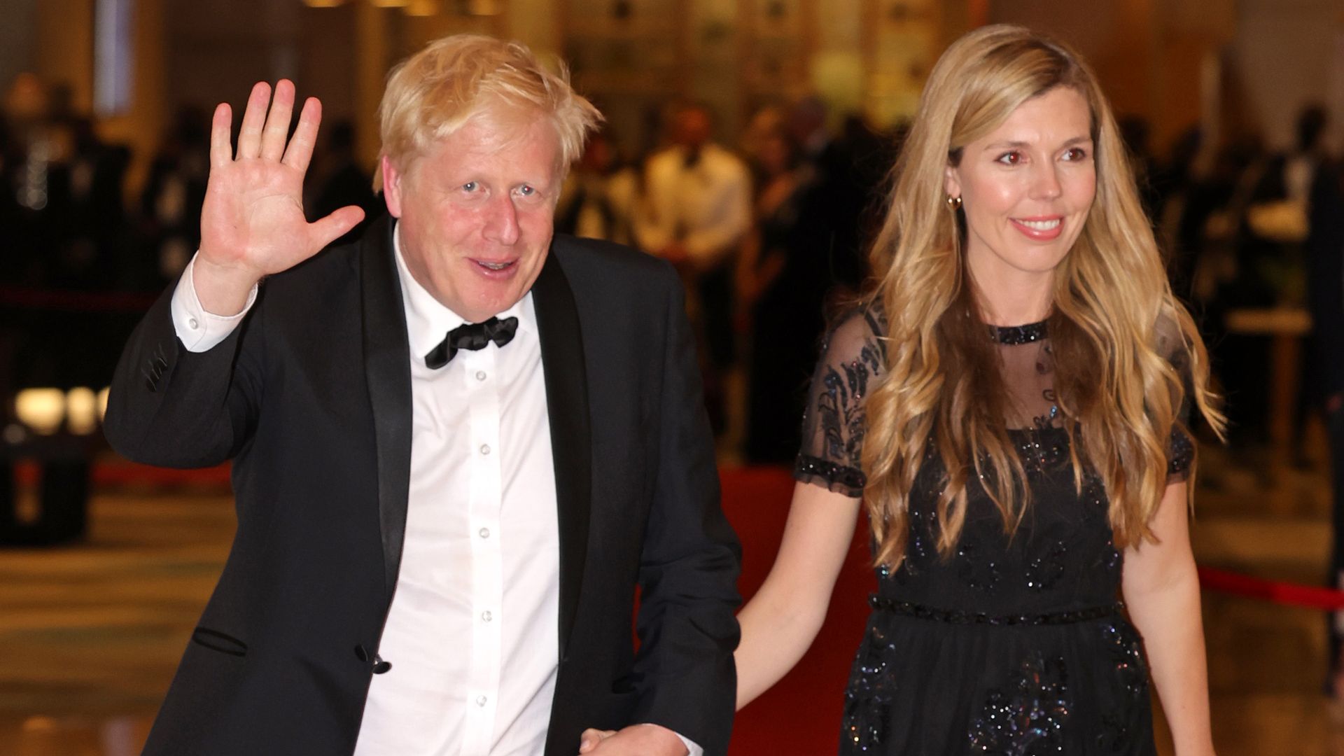 Boris Johnson in a suit walking with wife Carrie Johnson