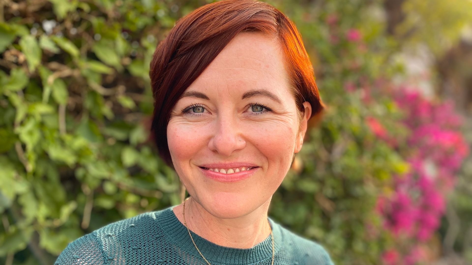 Author Bridget McNulty stands in front of a beautiful hedge