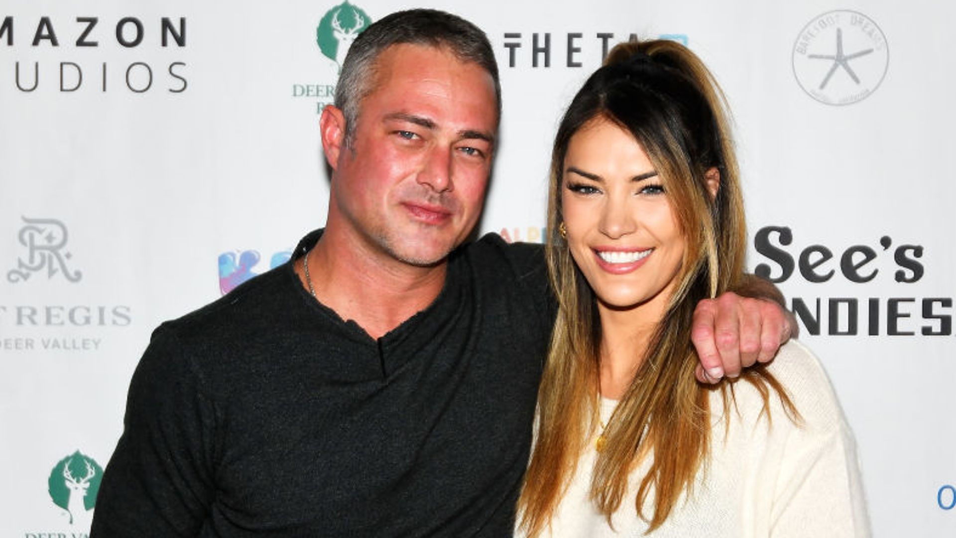 Ashley Cruger and Taylor Kinney cuddle up for a photo at a press event. 