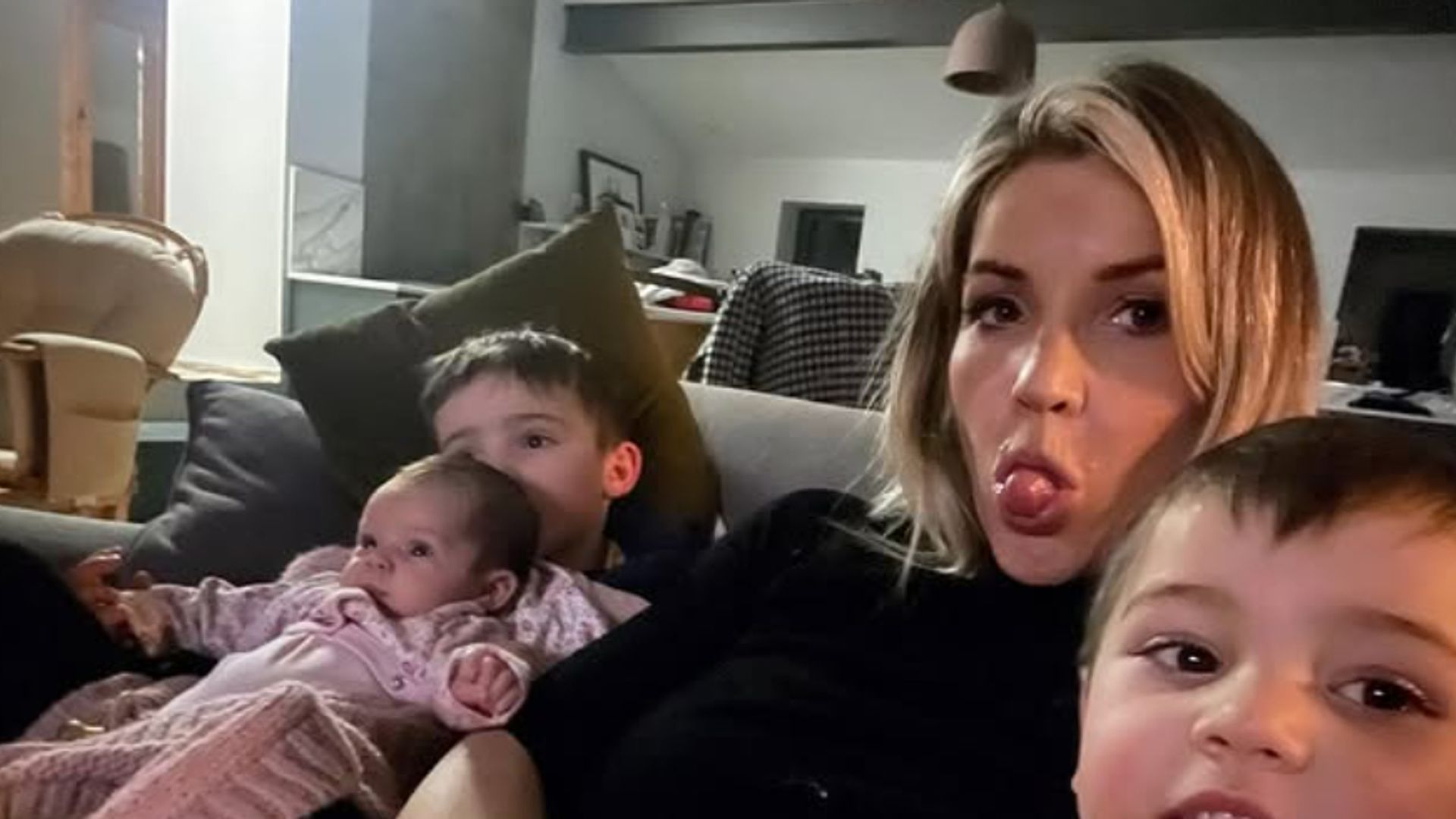 Helen Skelton with three children on a sofa - Helen is poking her tongue out