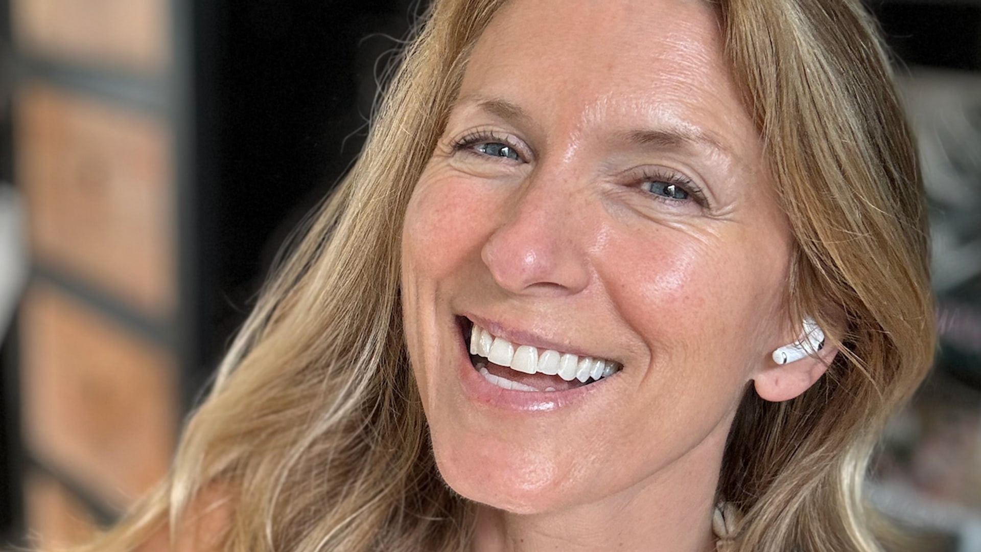 smiling blonde woman in a grey top posing for a selfie