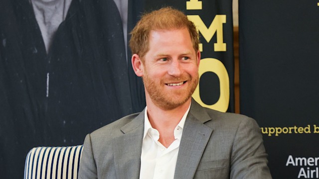 Prince Harry sitting in a chair while wearing a grey suit