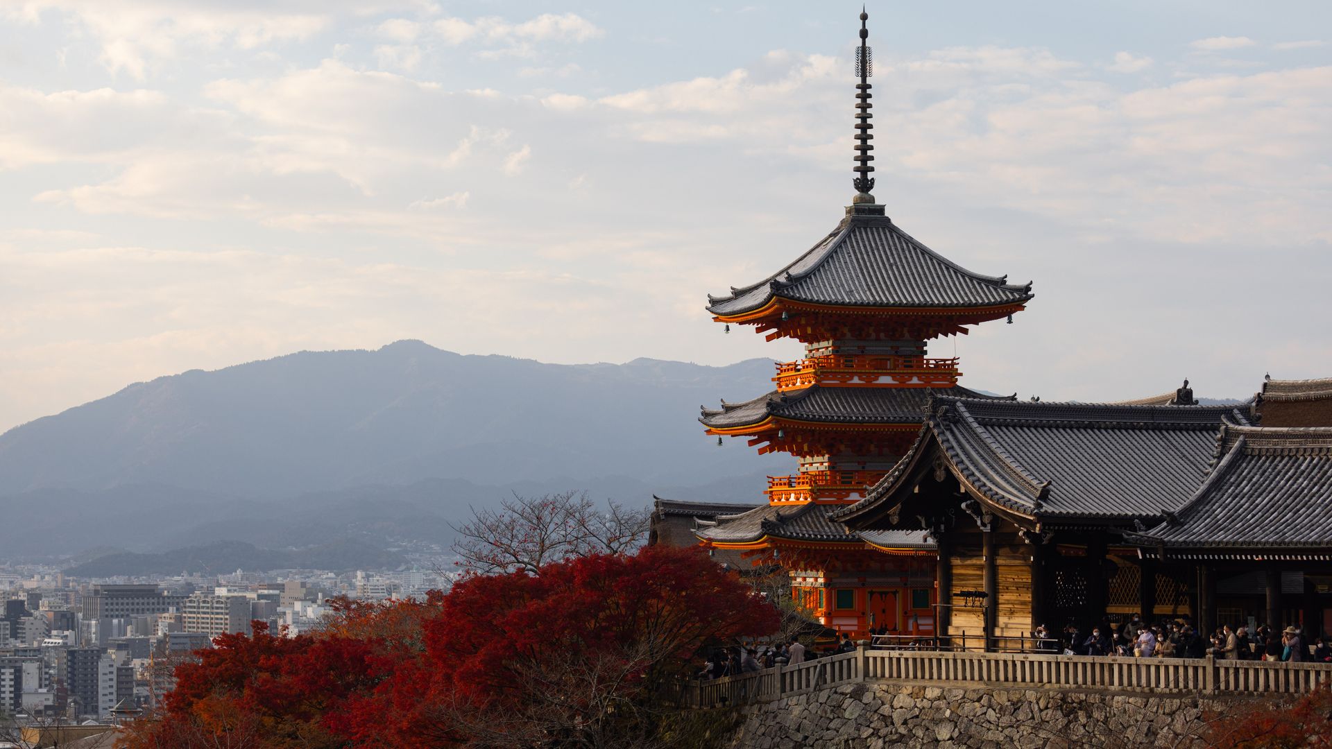 Three-storied Pagoda seen inside Kiyomizu-dera Buddhist temple in Kyoto surrounded by autumn colored leaves.