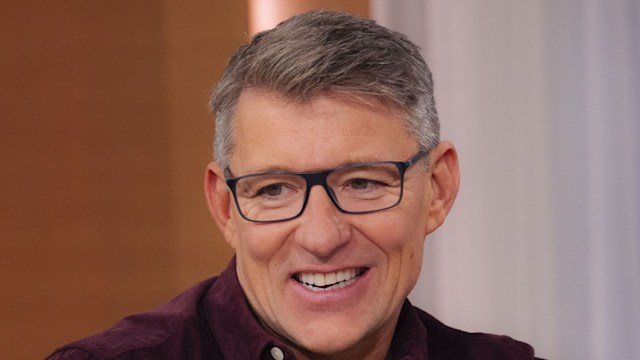 ben shephard laughing in maroon shirt on sofa