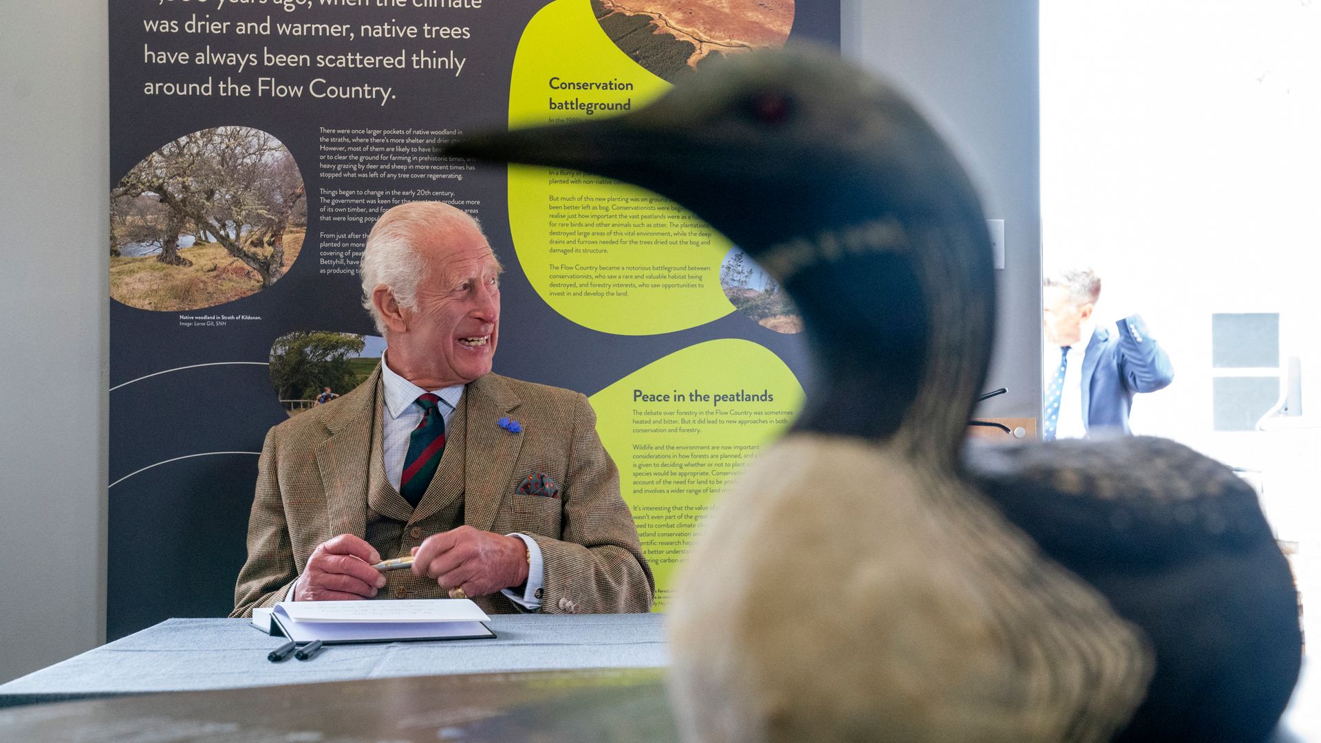 King Charles signs a visitors' book during a visit to the Forsinard Flows 