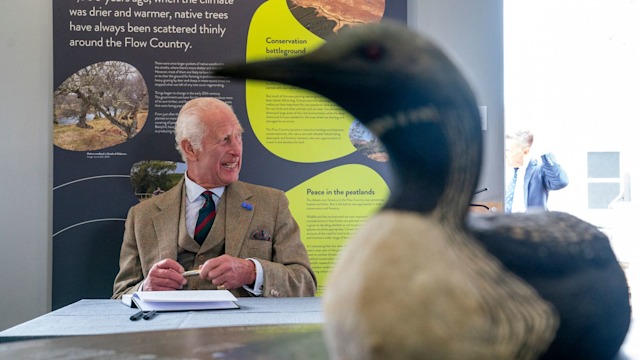 King Charles signs a visitors' book during a visit to the Forsinard Flows 