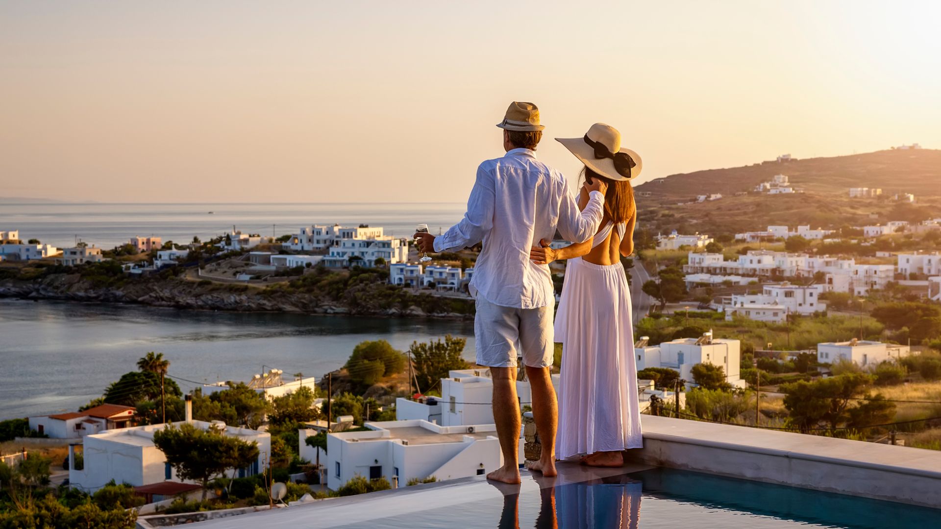 Happy couple on vacation time enjoying the summer sunset over the Aegean Sea
