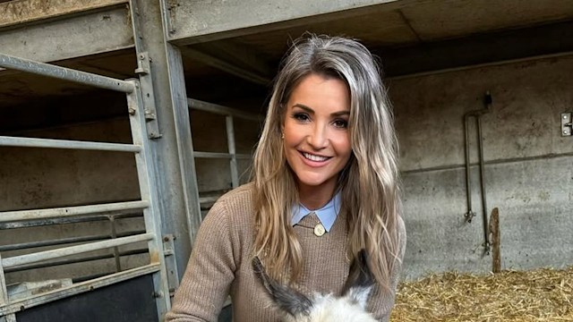 Woman kneeling on hay with baby donkey