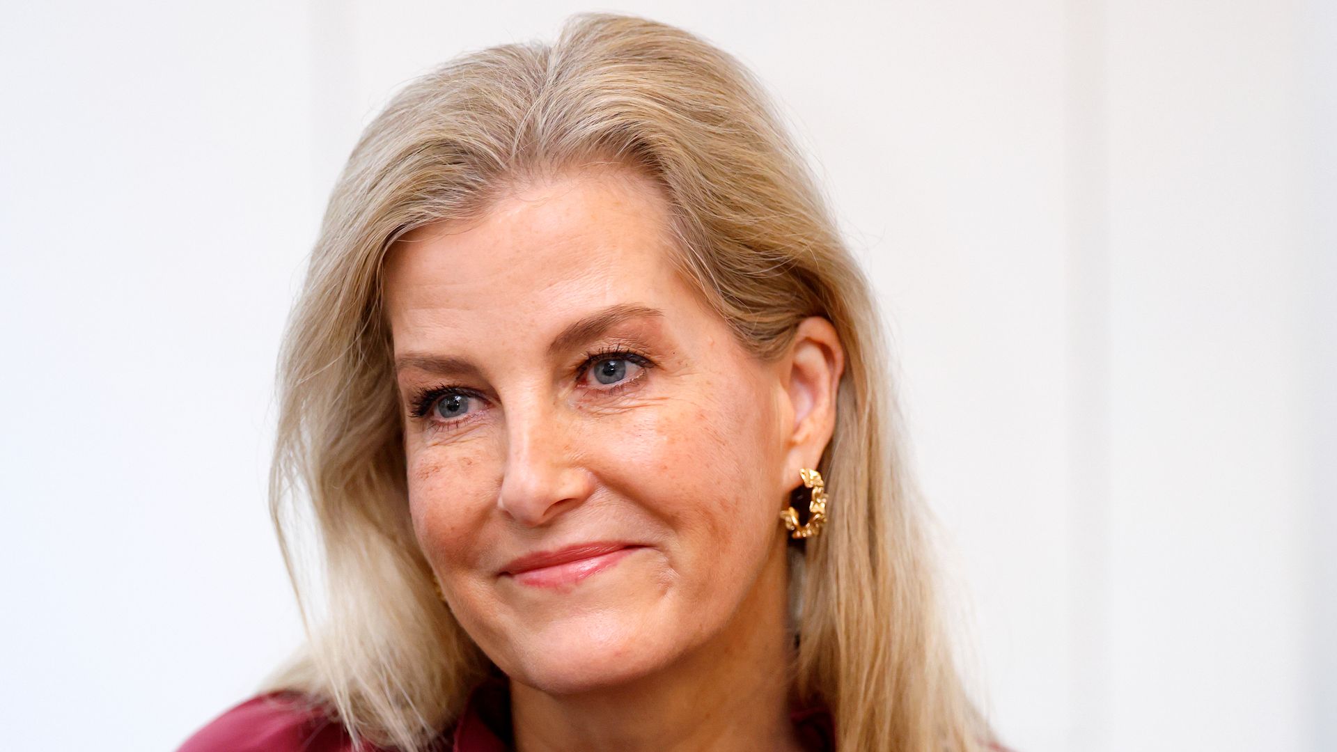 Duchess Sophie wearing burgundy blouse and gold hoop earrings