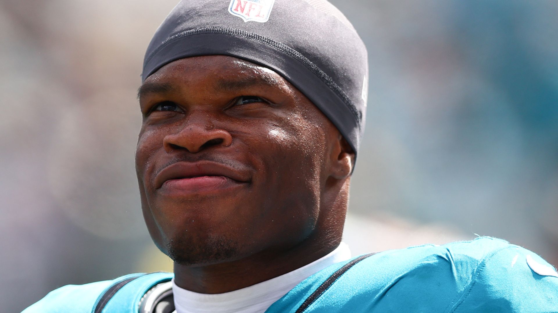 photo of travis hunter smiling wearing jaguars jersey and nfl hat