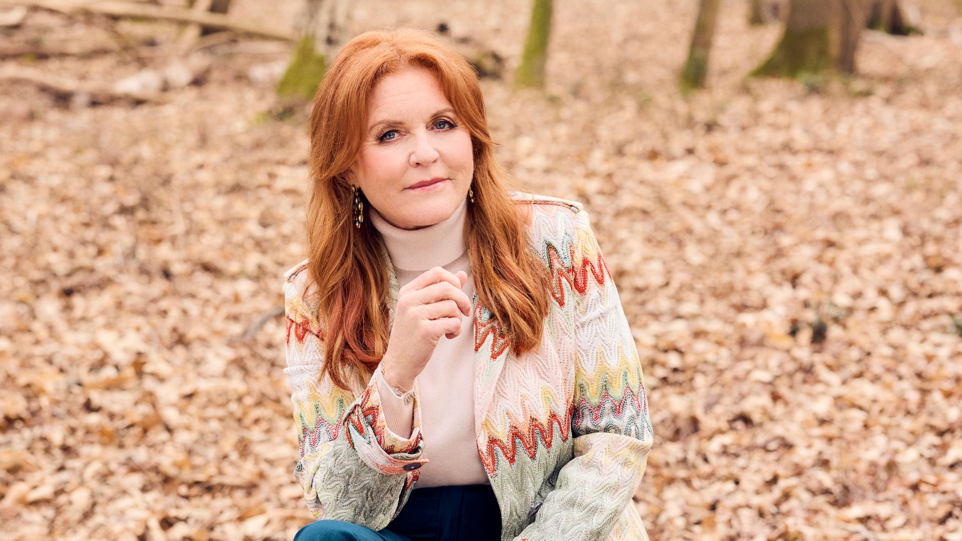 Sarah Ferguson sitting in a wood, wearing jeans and a cardigan