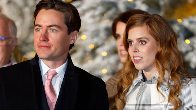 Princess Beatrice in a black and white coat with Edoardo in front of a white Christmas tree