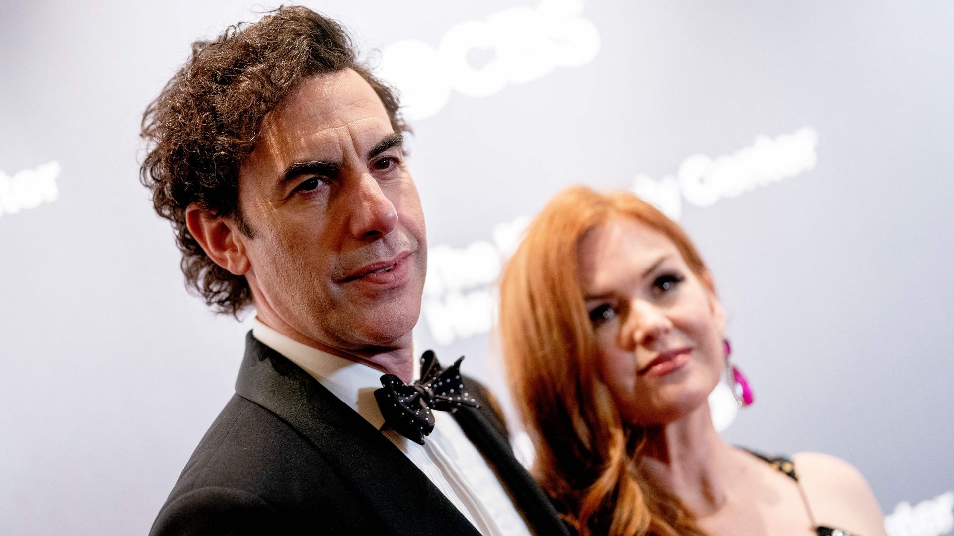 Sacha Baron Cohen and Isla Fisher in black tie on a red carpet