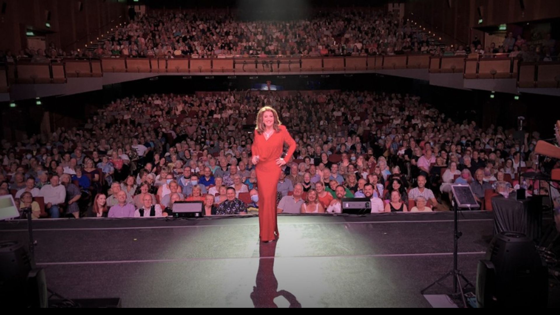 Jane McDonald in a red outfit in front of a crowd of people
