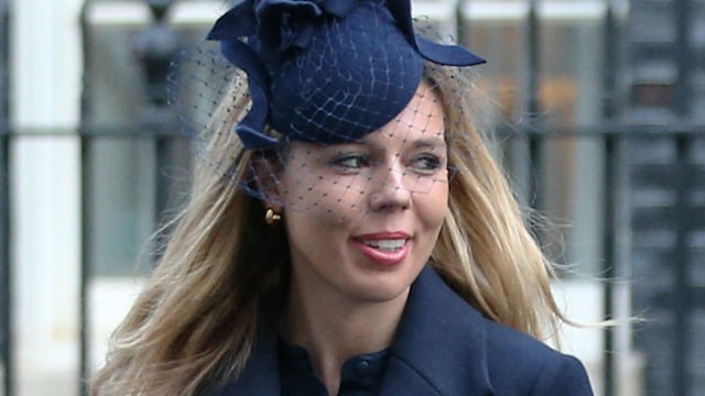 Carrie Johnson with a birdcage veil and blue coat looking sideways