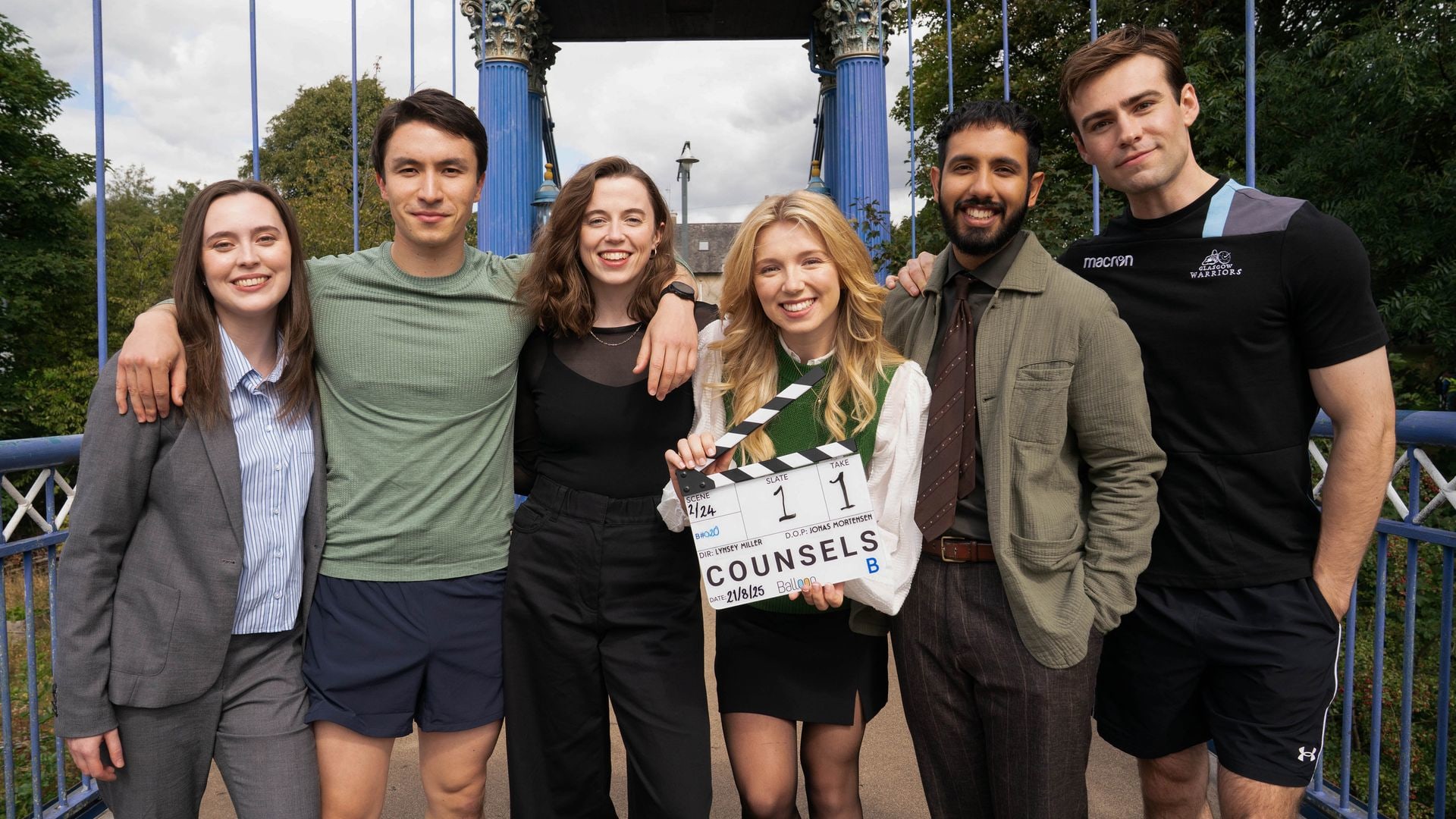 group of young people standing on bridge with clapper board