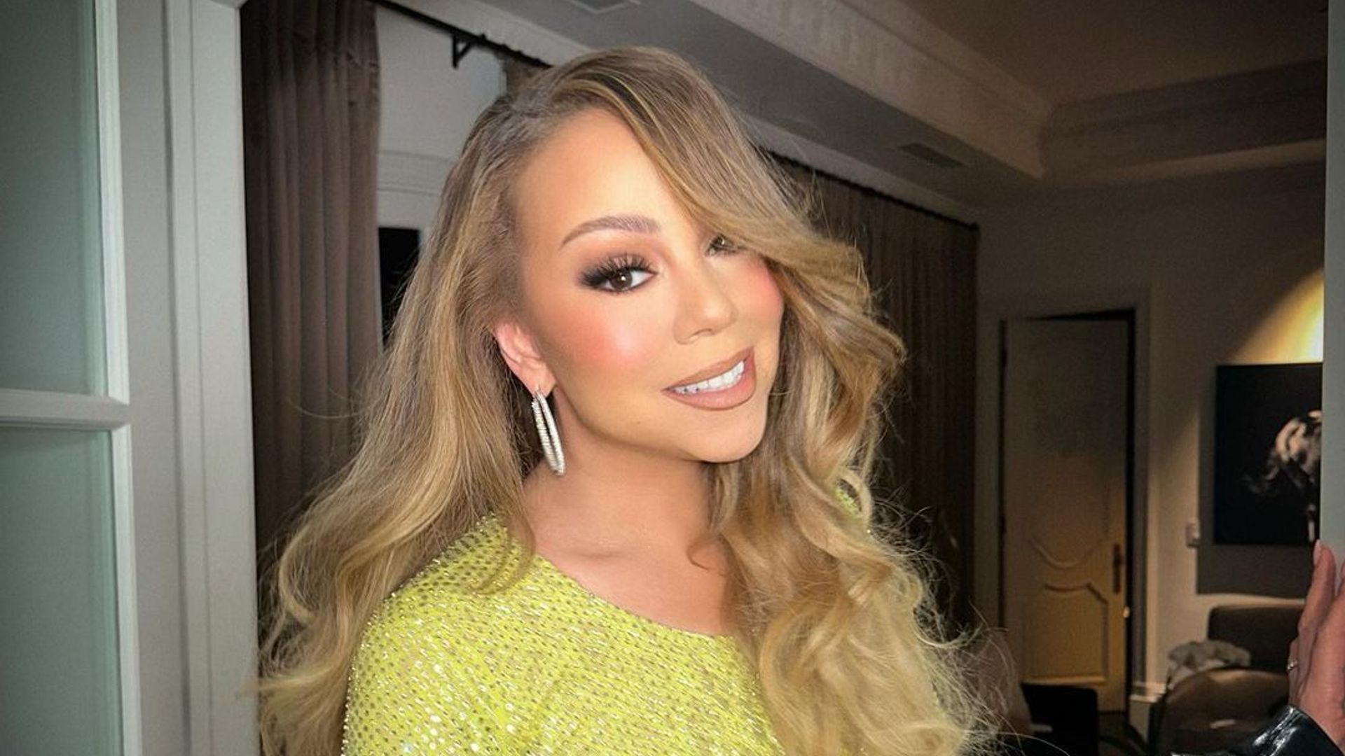 mariah carey wearing green bodycon sequin dress with curly hair posing in home
