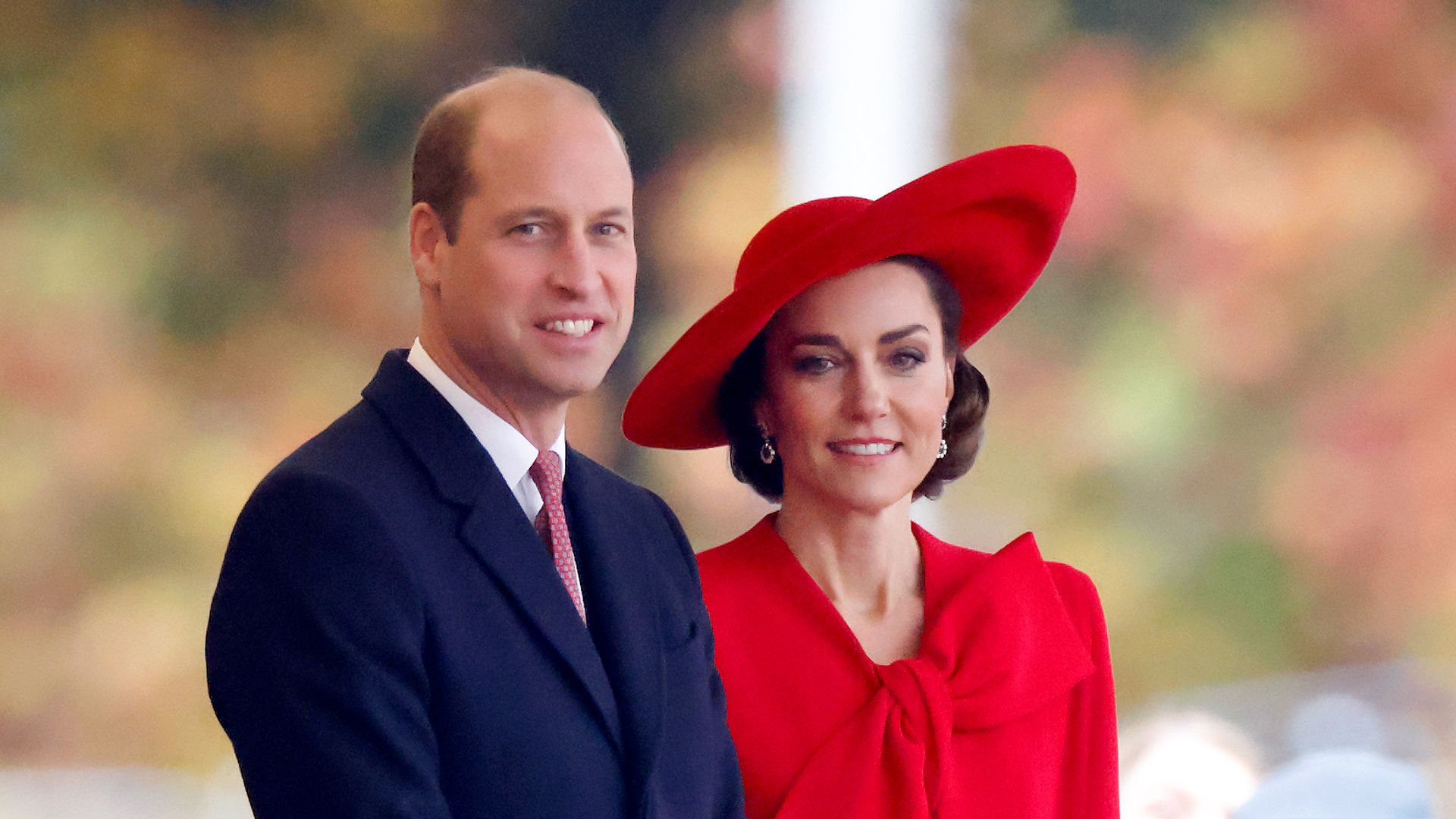 William and Kate standing at Horse Guards Parade in blue suit and red dress