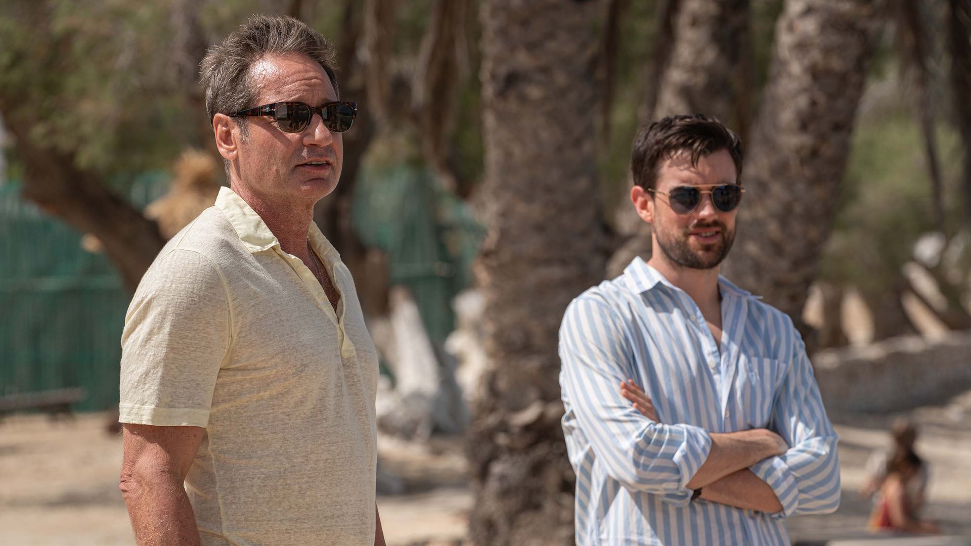 two men standin on beach wearing sunglasses
