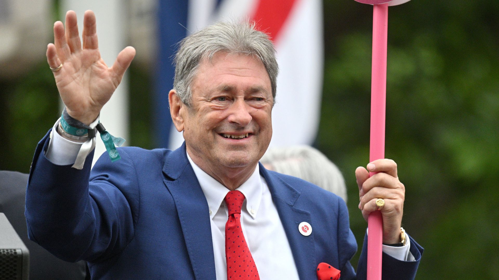 Alan Titchmarsh waving while carrying a pink paddle