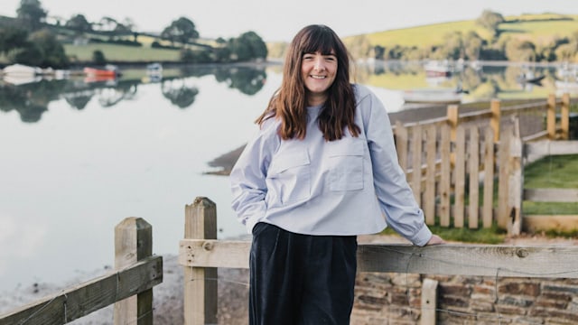 Woman standing in front of a river looking happy