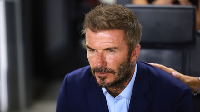 David Beckham looking serious in a blue suit and shirt