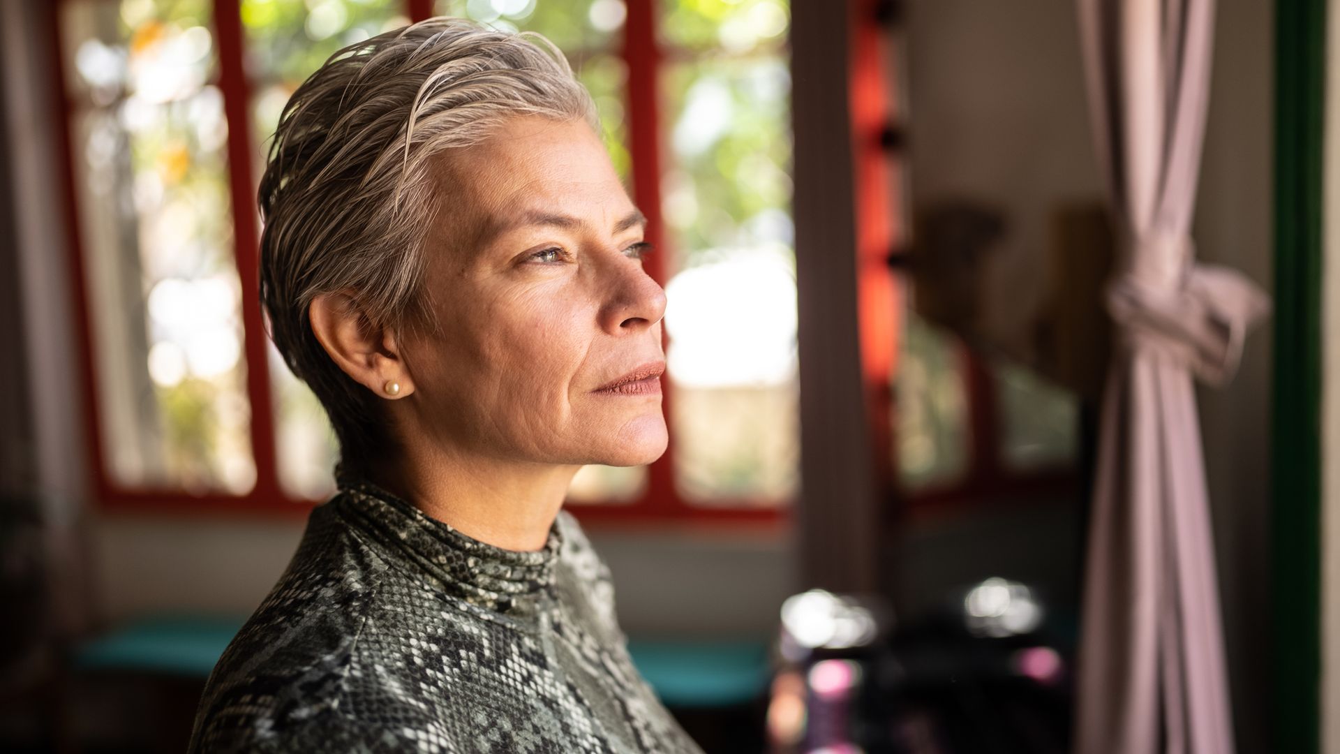 Contemplative mature woman looking through the view at home