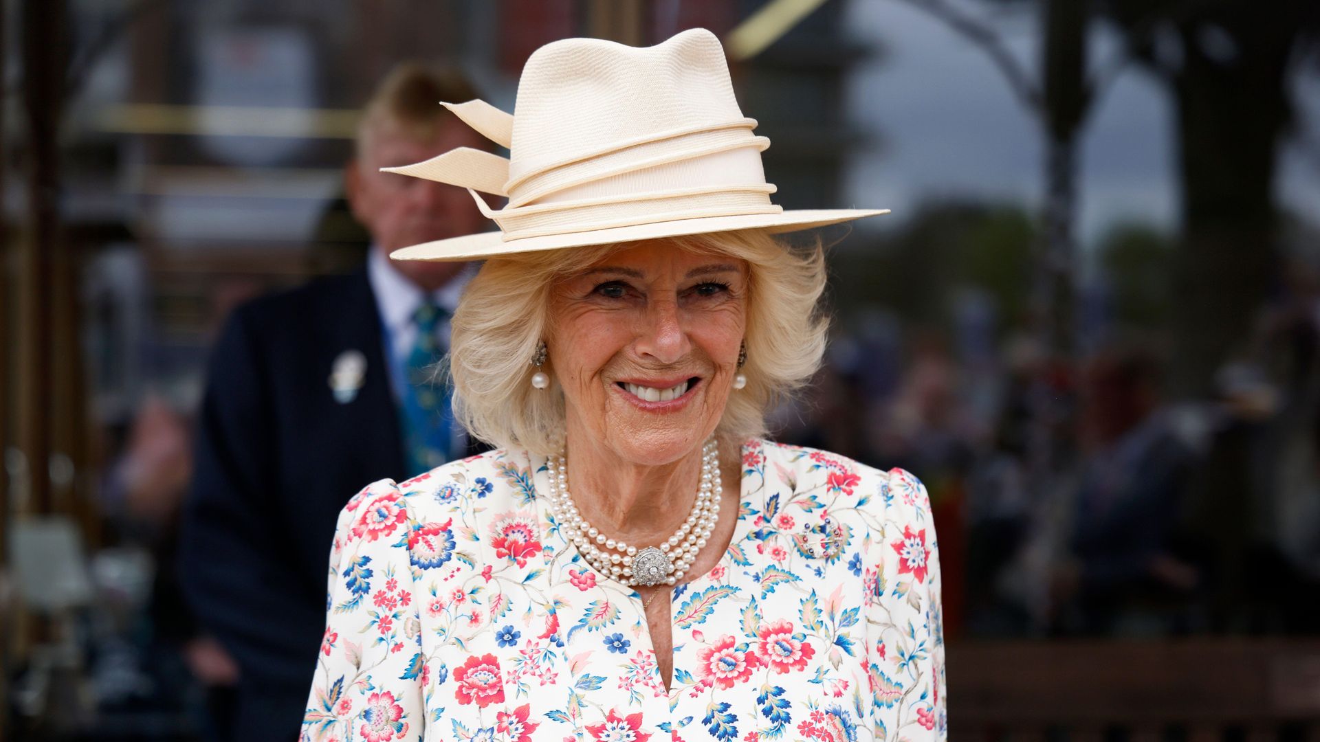 Queen Camilla smiles in floral dress and hat